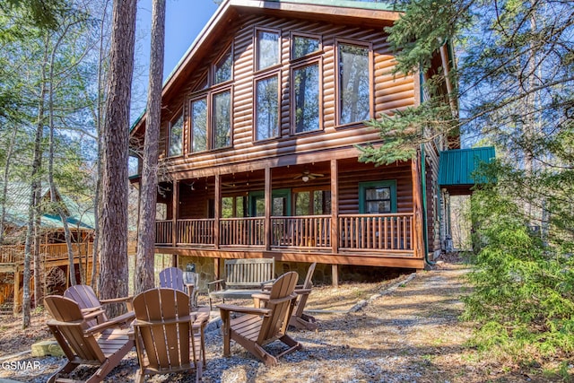 rear view of property with an outdoor fire pit, a wooden deck, and log veneer siding