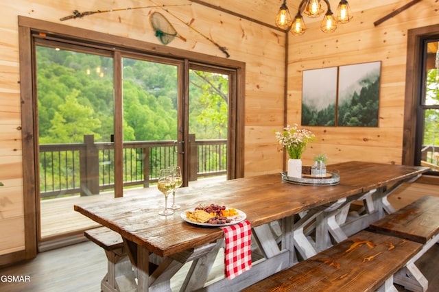 dining room with wooden walls, a chandelier, and a wealth of natural light