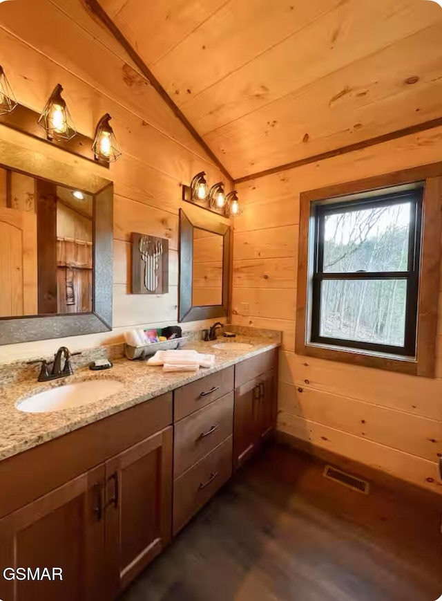 full bathroom with visible vents, a sink, wood finished floors, and vaulted ceiling