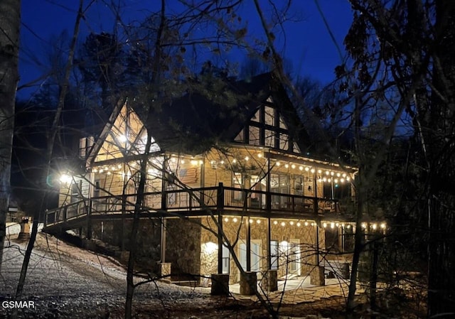 back of house at night with stone siding