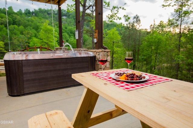 view of patio featuring a hot tub, a deck, and a forest view