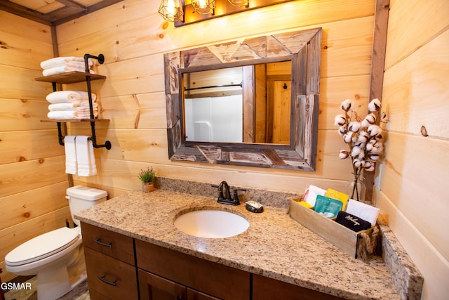 bathroom with vanity, wooden walls, and toilet