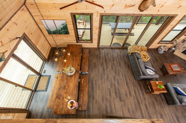 unfurnished living room featuring wooden walls, plenty of natural light, and wood finished floors