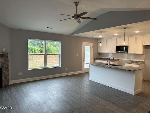 kitchen with stainless steel microwave, hanging light fixtures, visible vents, white cabinets, and a sink