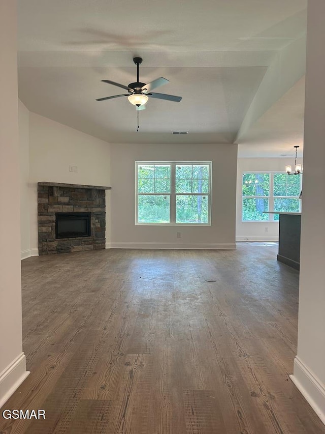 unfurnished living room with a fireplace, baseboards, wood finished floors, and ceiling fan with notable chandelier