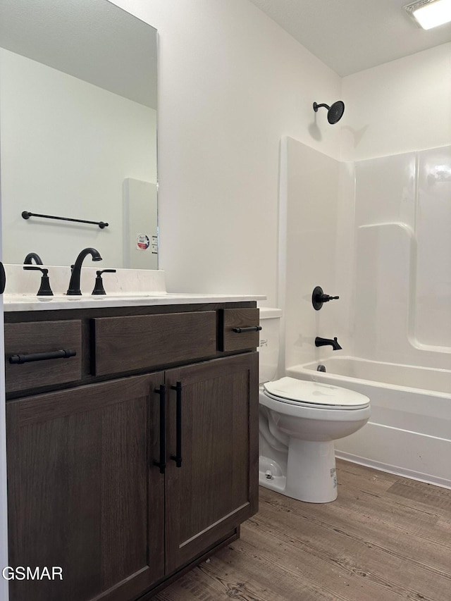 bathroom with visible vents, shower / bathing tub combination, toilet, vanity, and wood finished floors