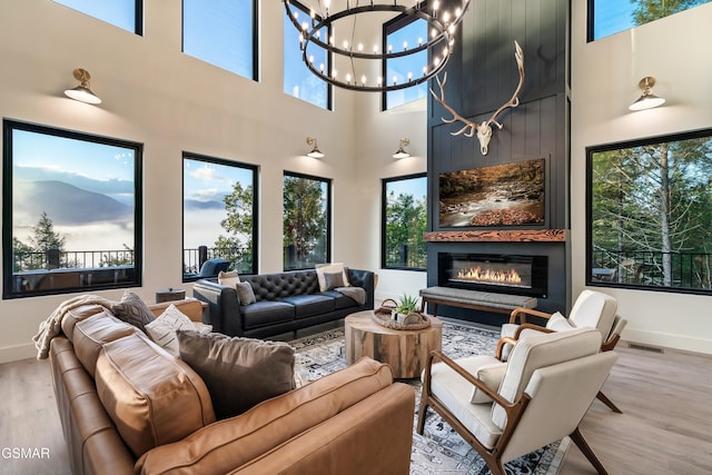 living area featuring a chandelier, visible vents, a fireplace, and wood finished floors