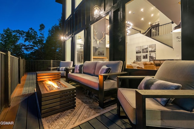 deck at night with an outdoor living space with a fire pit