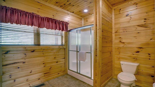 bathroom featuring tile patterned floors, wood ceiling, a shower with door, toilet, and wood walls