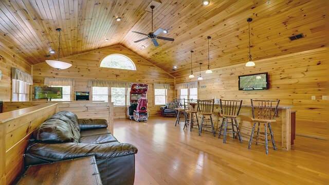 living room featuring wooden walls, light wood-type flooring, wooden ceiling, and high vaulted ceiling