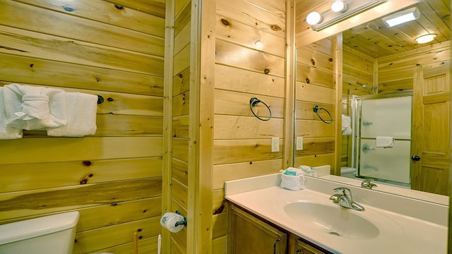 bathroom featuring vanity, toilet, a shower with shower door, and wooden walls