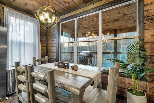 dining room featuring a chandelier, wood walls, plenty of natural light, and wooden ceiling