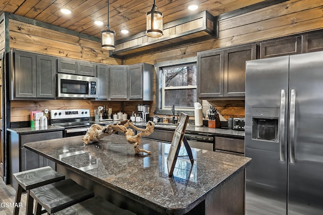 kitchen featuring appliances with stainless steel finishes, wood ceiling, pendant lighting, and wood walls