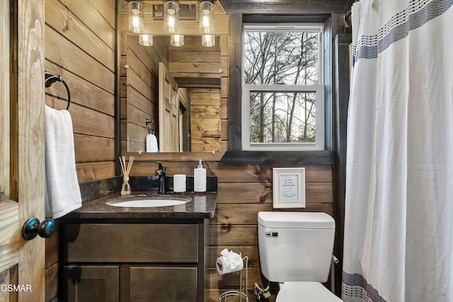 full bath with a shower with curtain, vanity, toilet, and wooden walls