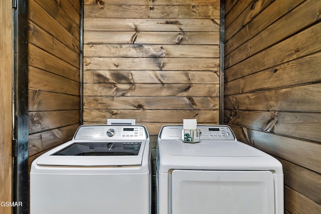 laundry room with laundry area, wood walls, and separate washer and dryer