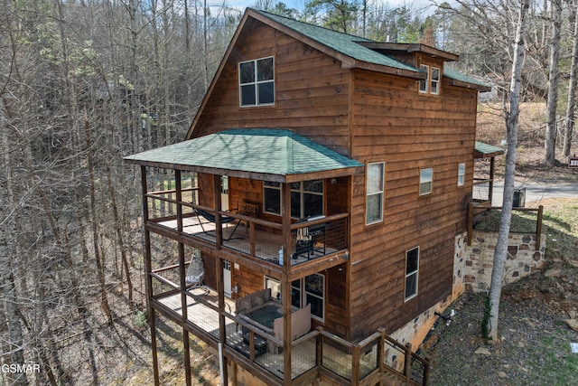 rear view of property featuring roof with shingles and a wooden deck