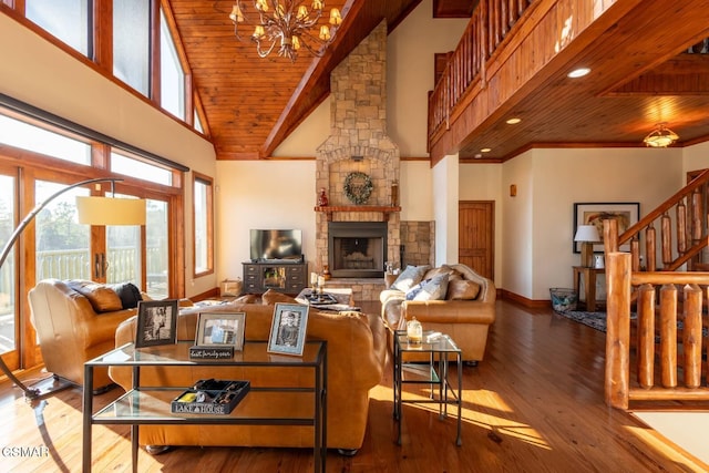 living room featuring hardwood / wood-style floors, wood ceiling, a towering ceiling, a stone fireplace, and an inviting chandelier