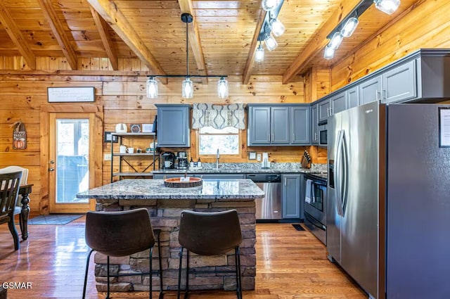 2430 Cobbler Way, Pigeon Forge, TN 37863 - kitchen featuring appliances with stainless steel finishes, a wood ceiling with exposed beams, light wood finished floors, a center island, and light stone countertops