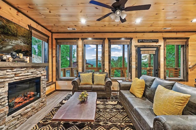 living room featuring ceiling fan, wood-type flooring, wooden walls, a fireplace, and wood ceiling