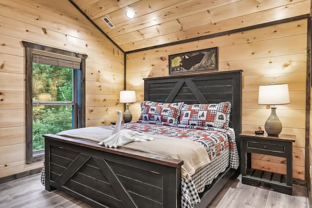 bedroom with wood-type flooring, wood ceiling, wooden walls, and vaulted ceiling