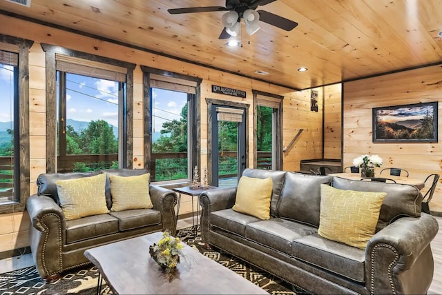 living room featuring a healthy amount of sunlight, ceiling fan, wood walls, and wood ceiling