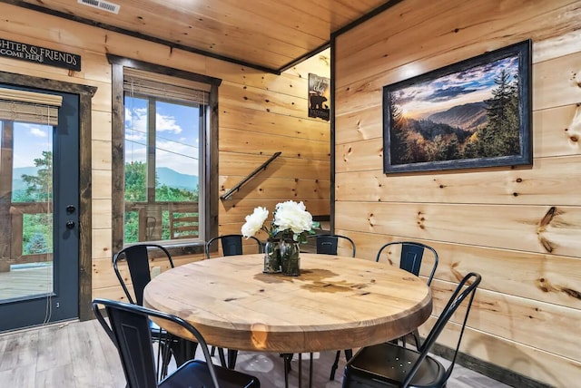 dining area with wood walls, wood-type flooring, wooden ceiling, and a healthy amount of sunlight