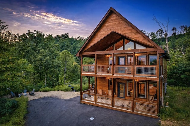 back house at dusk featuring a porch and a balcony