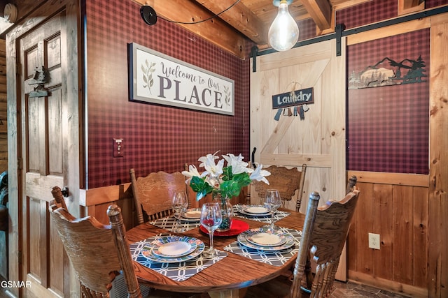 dining room with a barn door and wood walls