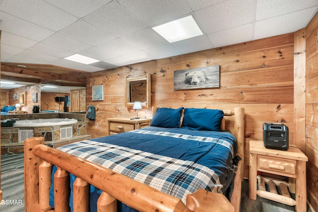 bedroom featuring a drop ceiling and wood walls