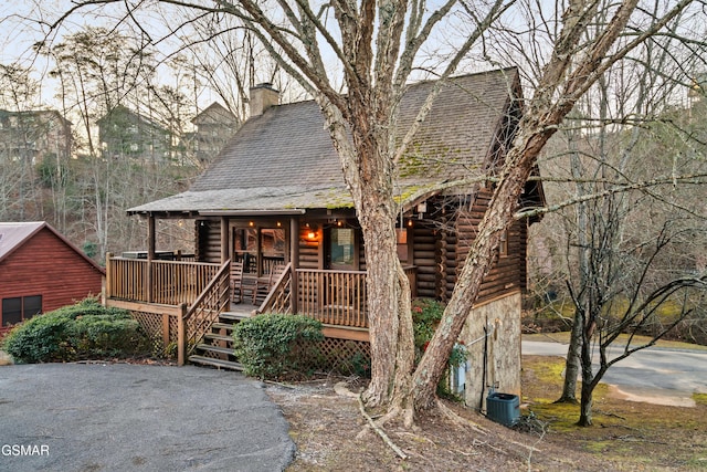 log-style house with covered porch and central AC unit