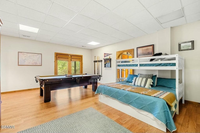 bedroom with a drop ceiling, baseboards, and wood finished floors