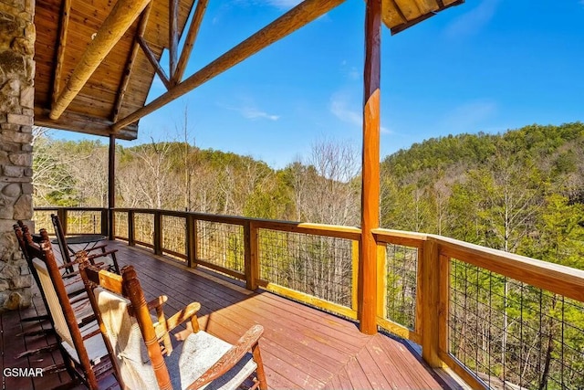 wooden terrace featuring a view of trees