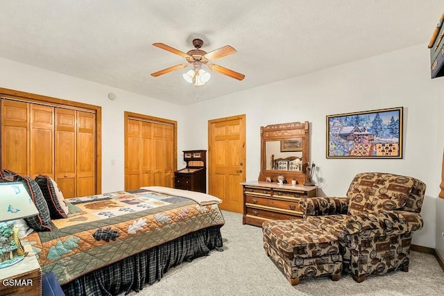 carpeted bedroom with two closets and a ceiling fan