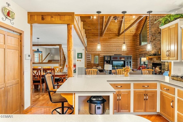 kitchen with a stone fireplace, light countertops, a kitchen bar, and light wood-style floors