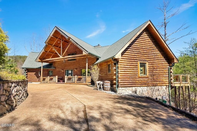 back of property with log exterior and roof with shingles