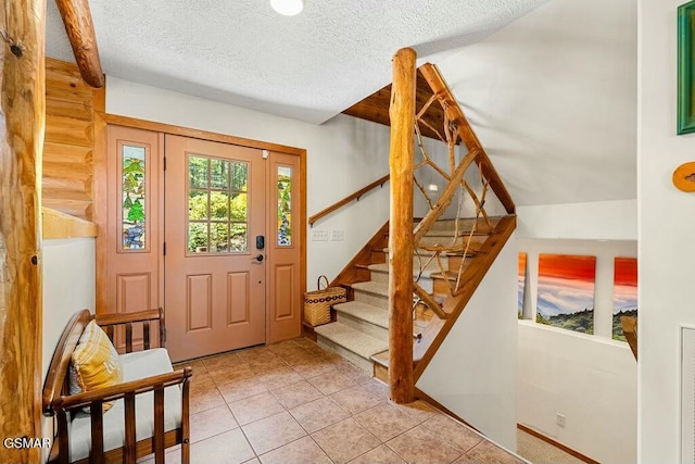 foyer featuring stairs, light tile patterned flooring, and a textured ceiling