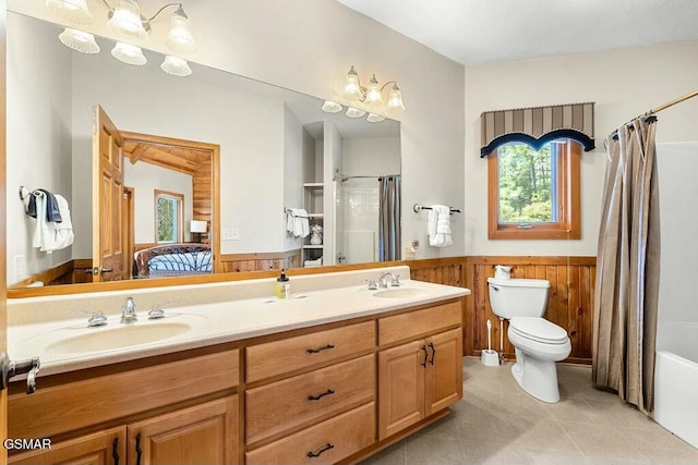 bathroom with toilet, a wainscoted wall, wood walls, and a sink