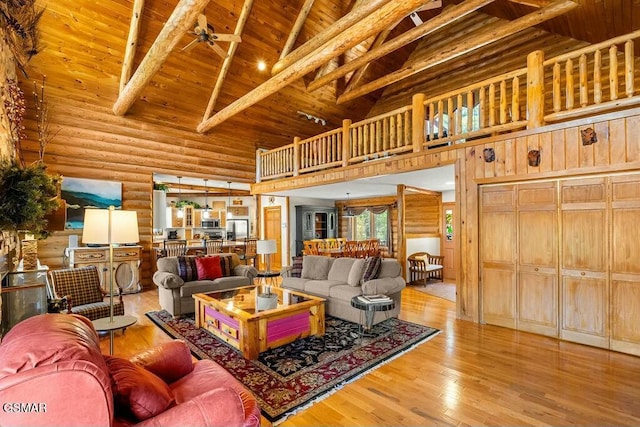 living area with beam ceiling, high vaulted ceiling, wood finished floors, log walls, and wood ceiling