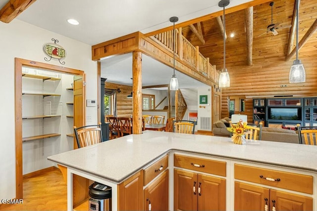 kitchen featuring beamed ceiling, open floor plan, light countertops, and light wood-style flooring