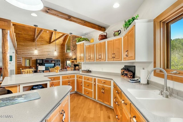 kitchen featuring beam ceiling, a sink, recessed lighting, light wood-style floors, and a peninsula