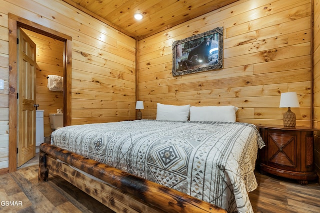 bedroom featuring hardwood / wood-style flooring, wooden walls, and ensuite bath