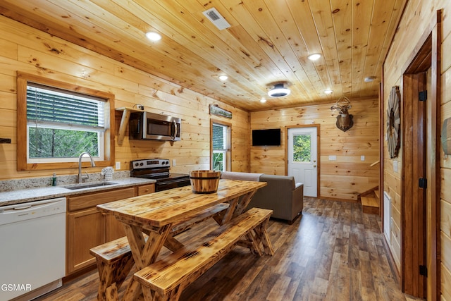 kitchen with dishwasher, sink, dark wood-type flooring, black electric range, and wooden walls