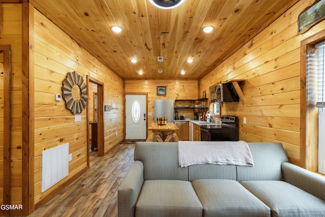 living room featuring hardwood / wood-style flooring, wooden ceiling, sink, and wooden walls