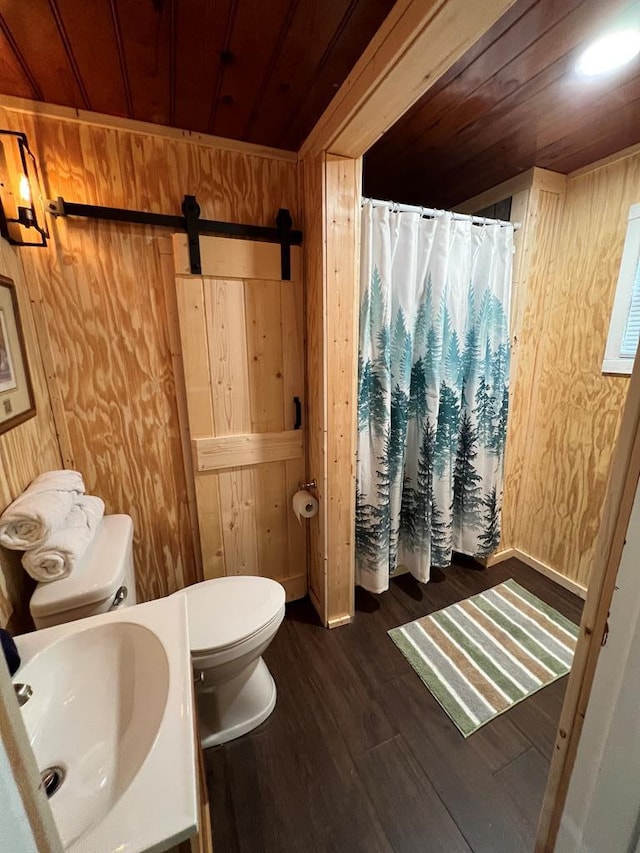 bathroom featuring sink, wood walls, hardwood / wood-style floors, toilet, and wood ceiling