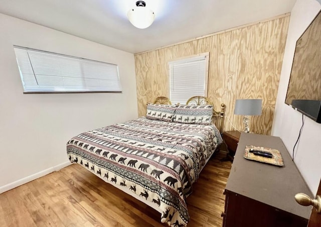 bedroom featuring hardwood / wood-style flooring and wooden walls