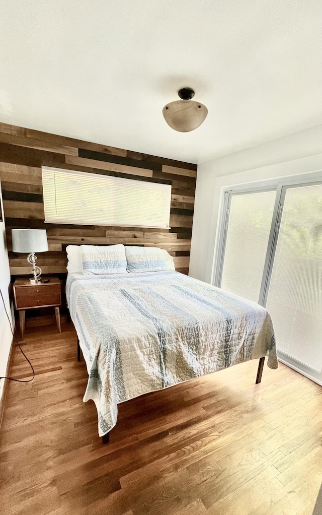 bedroom with wood-type flooring and wooden walls