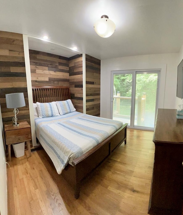 bedroom with wood walls and light hardwood / wood-style flooring