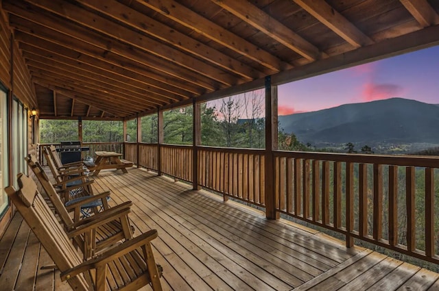 deck at dusk with a mountain view and grilling area