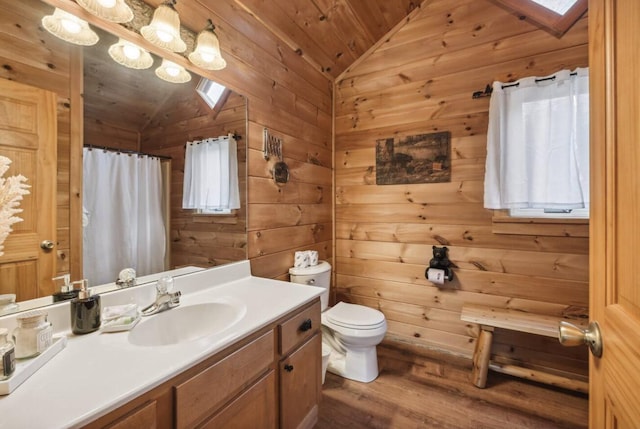 bathroom featuring vaulted ceiling with skylight, vanity, wood walls, and wooden ceiling