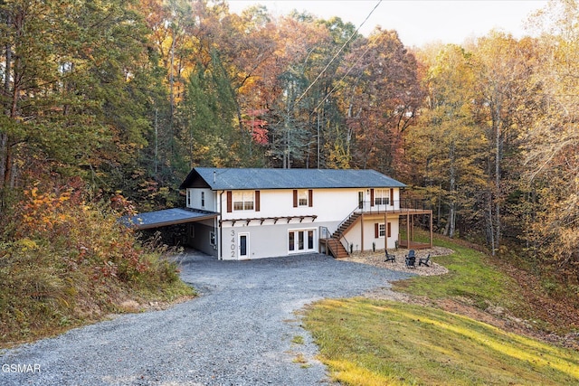 front facade with french doors, a deck, and a front lawn